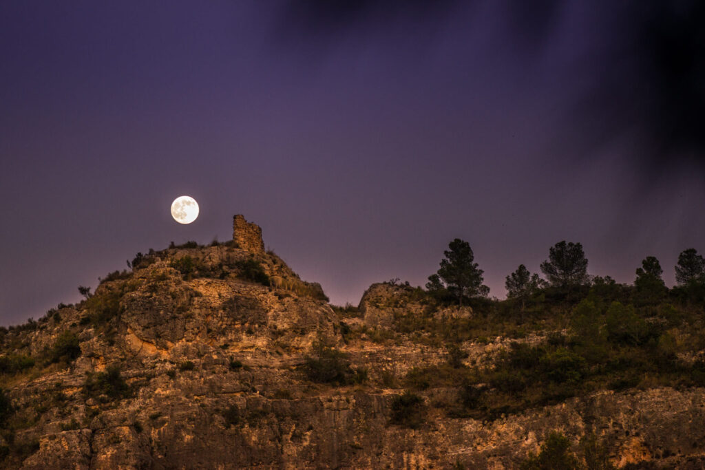 Luna llena ascendiendo sobre el Castillo de Penyarroja en Sumacàrcer